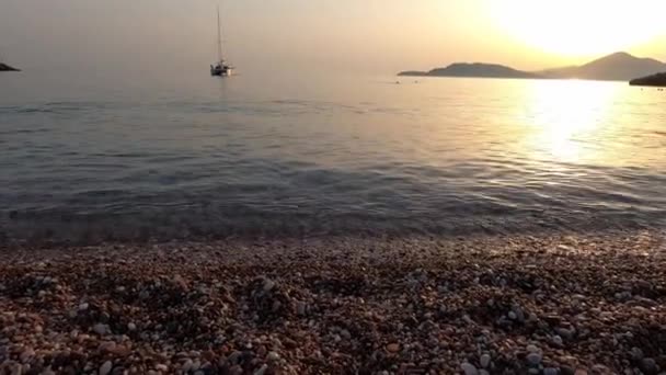 在夕阳西下的背景下 从卵石铺就的海滩上眺望大海中的帆船 高质量的4K镜头 — 图库视频影像