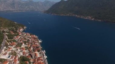 Mavi denizin kıyısındaki antik Perast kasabası yüksek bir dağ silsilesiyle çevrilidir. Drone. Yüksek kalite 4k görüntü