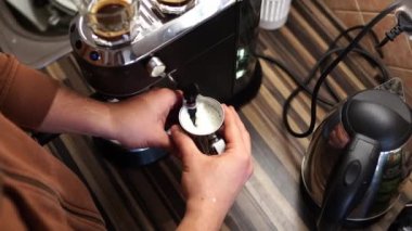 Barman finishes frothing milk in a metal jug and presses the lever of the coffee machine. High quality 4k footage