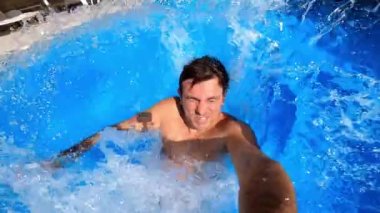 Young man jumps into the pool backwards and dives into the water. High quality FullHD footage