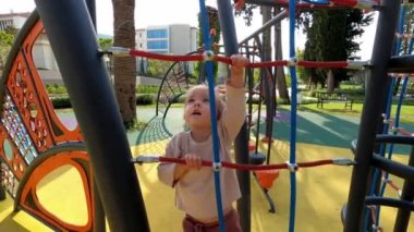 Little girl climbing up the rope ladder at the playground. High quality 4k footage