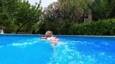 Mom pushes a little girl on an inflatable ring in the pool. High quality 4k footage