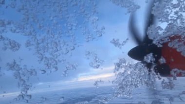 View from the snow-covered window of the aircraft on the spinning propeller of the engine. High quality 4k footage