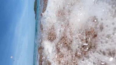 Beyaz köpüklü deniz dalgaları çakıl taşı plajında yuvarlanıyor. Yakın plan. Yüksek kalite 4k görüntü