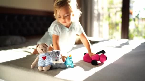 Маленька Дівчинка Повзає Які Іграшки Ліжку Грає Ними Високоякісні Кадри — стокове відео