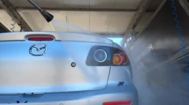 Trunk and taillights of a car being washed with a hose at a car wash. High quality 4k footage