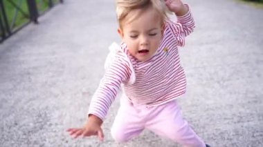Little girl walks along an asphalt path and falls on her stomach. High quality FullHD footage