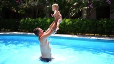 Dad jumping in the pool with a little girl in his arms. High quality FullHD footage