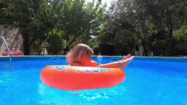 Dad spins a little girl on an inflatable ring in the pool. High quality 4k footage