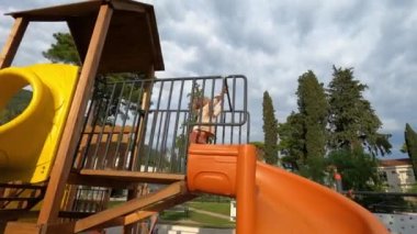Küçük kız renkli bir oyun parkında spiral bir kaydırağın içine giriyor. Yüksek kalite 4k görüntü