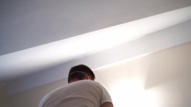Man in a mask with a cleaning spray removes mold on the ceiling. High quality 4k footage
