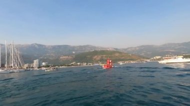 Dağ kıyısı boyunca kırmızı feribot denizde yüzüyor. Karadağ. Yüksek kalite 4k görüntü