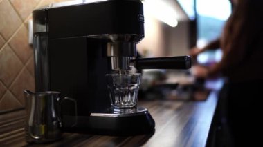 Coffee machine with a glass on a tray on a table against the background of a man grinding coffee beans. High quality 4k footage