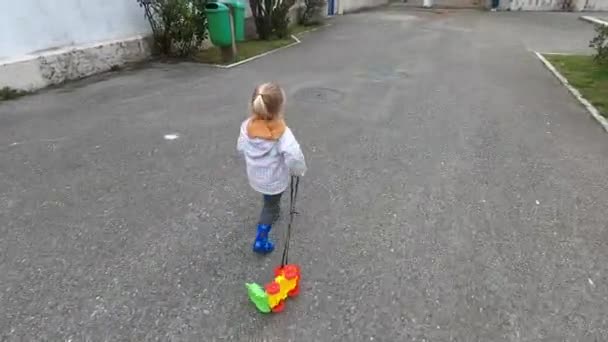 Little Girl Runs Toy Car Rope Asphalt Yard High Quality — Vídeos de Stock