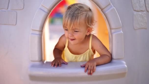 Little Girl Looks Out Window Toy House Showing Her Tongue — Stock Video
