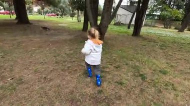 Little girl runs through the green garden trying to keep up with the cat. High quality 4k footage