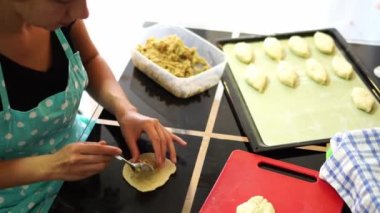 Woman spooning stuffing on a piece of dough for a bun. High quality 4k footage