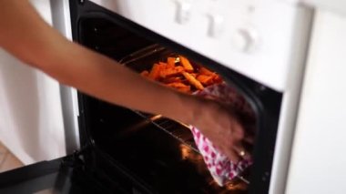 Woman takes a baked sweet potato out of the oven in a deep dish. High quality 4k footage
