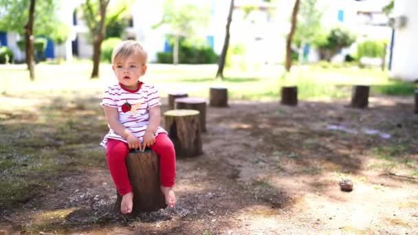 光着脚的小女孩坐在树桩上吊着腿 高质量的4K镜头 — 图库视频影像