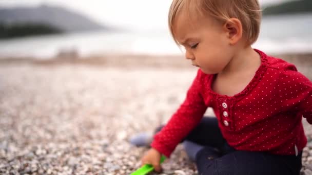 Ein Kleines Mädchen Sitzt Strand Und Gräbt Mit Einer Spielzeugharke — Stockvideo
