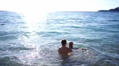 Dad carries a little girl in his arms on the waves. High quality 4k footage