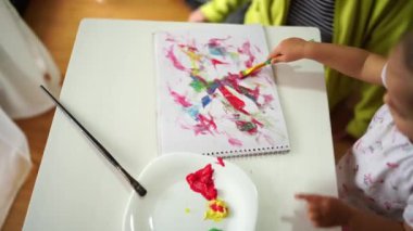 Little girl draws with a brush in the album. High quality 4k footage