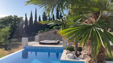 Swimming pool with turquoise water in the garden with palm trees and sun loungers. High quality 4k footage