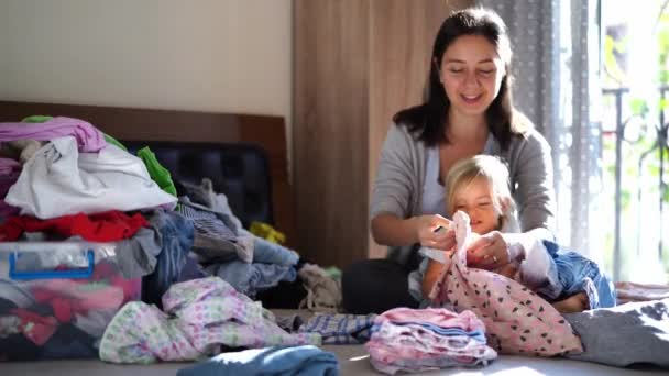 Mom Little Girl Stack Washed Baby Clothes Piles While Sitting — Stockvideo