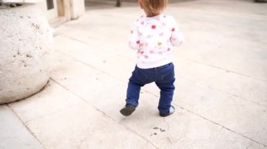 Small child walks in the tiled yard near the house. High quality FullHD footage