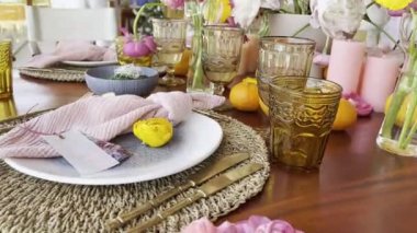 Bouquets of flowers in vases stand on a laid table next to candles and fruits. High quality 4k footage