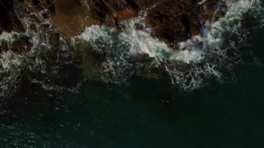 Ocean hits a deserted rocky shore, raising spray. High quality 4k footage