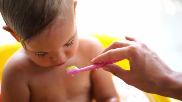 お母さんの手は水の流域に座っている少女に歯ブラシで歯をきれいにします 高品質4K映像 — ストック動画
