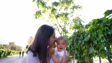 Mom kisses and hugs a shifting little girl, leaning forward with her. High quality 4k footage