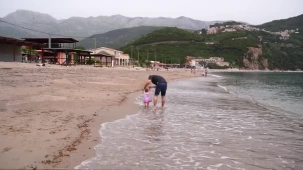 Papá Lleva Una Niña Por Mano Largo Orilla Del Mar — Vídeos de Stock