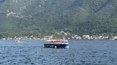 Sahilin arka planında yeşil dağları olan bir tekne denizde yüzüyor. Yüksek kalite 4k görüntü