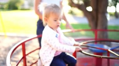 Mom rides a little girl sitting on the seat on a carousel. High quality 4k footage
