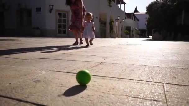 小さな女の子は転がるボールの後 タイル張りの床の上を歩くと 彼女の母親の手を保持 高品質のフルHd映像 — ストック動画