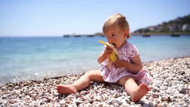 Uma Menina Descalça Senta Praia Come Uma Banana Imagens Alta — Vídeo de Stock
