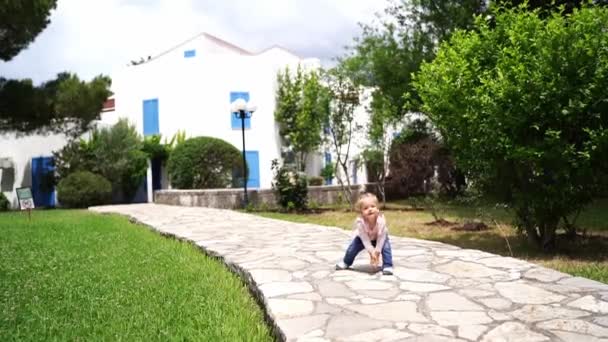 少女は立ち上がって庭のタイル張りの道を歩く 高品質のフルHd映像 — ストック動画