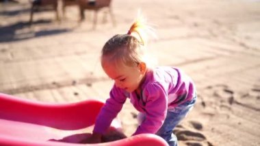 Little girl pours sand on a slide and removes it on the beach. High quality 4k footage