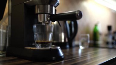 Coffee from a coffee machine dripping into a glass on a stand. High quality 4k footage