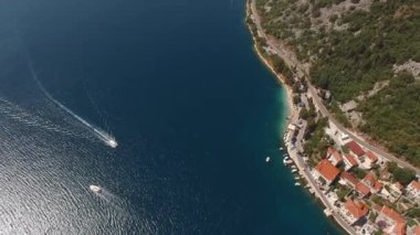 Boats float on the sea past the coast of Perast. Montenegro. Aerial view. High quality 4k footage