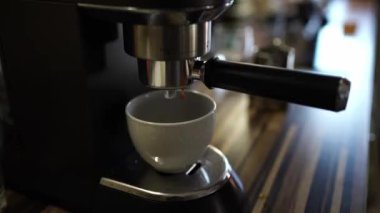 Coffee from the coffee machine drips into a cup on a tray. High quality 4k footage