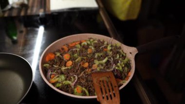 Cook takes a baking sheet out of the oven, then stirs the minced meat with vegetables in a pan. High quality 4k footage