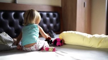Little girl pushes a toy car while crawling on the bed. High quality 4k footage