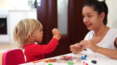 Mom teaches a little girl to sculpt crafts from plasticine at the table. High quality 4k footage