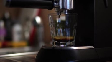 Coffee is brewed in a carob coffee machine and dripped into a glass on the tray. High quality 4k footage