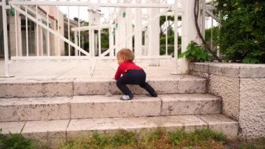 Little girl crawls backwards down the stone steps in the park. High quality 4k footage