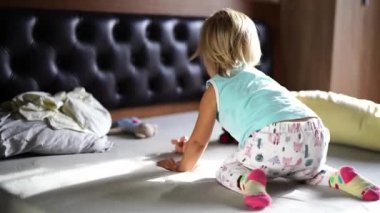 Little girl playing with a toy car while crawling on the bed. High quality 4k footage