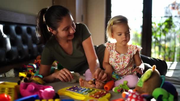 妈妈和小女孩在床上玩五彩缤纷的玩具 高质量的4K镜头 — 图库视频影像